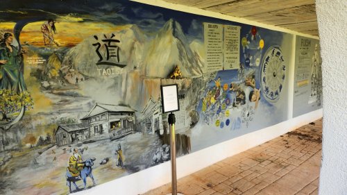 A colorful mural depicting landscapes, figures, and text, showcasing cultural themes and artistic elements.