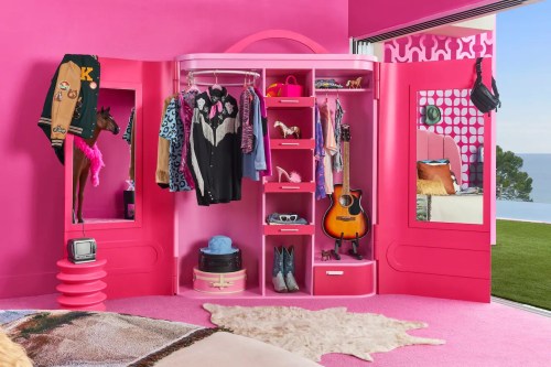 A vibrant pink closet filled with colorful clothes, accessories, and a guitar, set in a stylish room with a view.