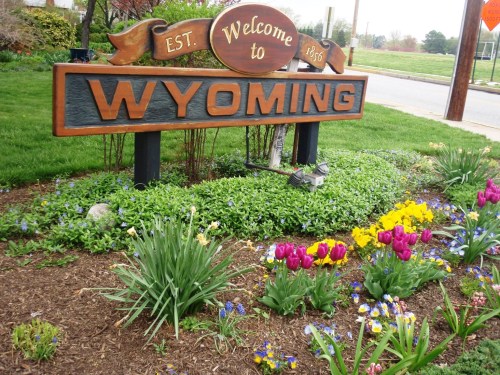 Welcome sign for Wyoming surrounded by colorful flowers and greenery. Established in 1836.