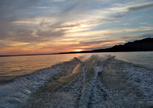 A serene sunset over water, with gentle waves and a colorful sky reflecting on the surface.