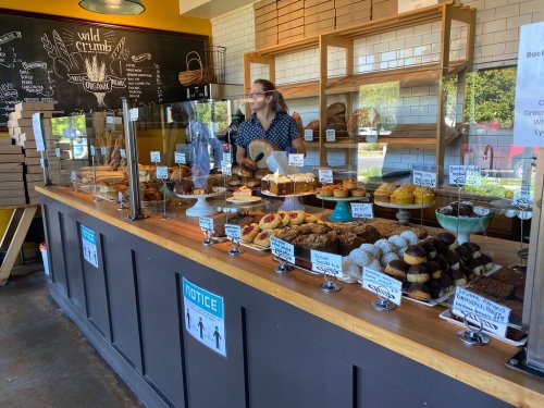 A bakery display filled with various pastries and desserts, with a staff member behind the counter.