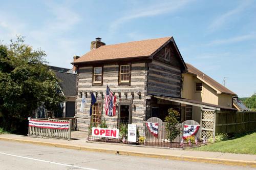 A charming log cabin-style building with an "OPEN" sign and patriotic decorations, set against a clear blue sky.