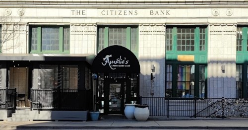 Exterior of Amélie's French Bakery & Café, featuring a black awning and large windows, next to The Citizens Bank building.