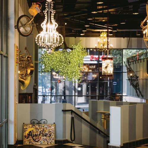 A vibrant interior featuring unique decor, chandeliers, and a whimsical bicycle hanging from the ceiling.