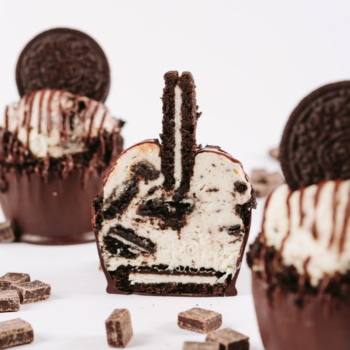 A cross-section of an Oreo cupcake, revealing layers of cookie and cream, topped with chocolate drizzle and an Oreo cookie.