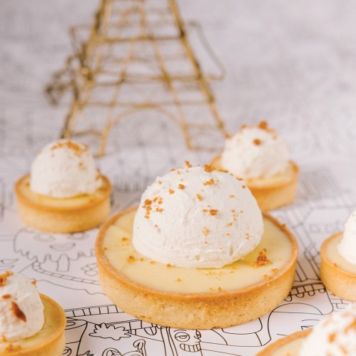 Delicious tarts with creamy filling and whipped cream, set against a whimsical background featuring the Eiffel Tower.