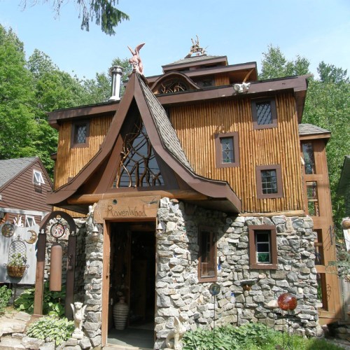 A unique, whimsical house with wooden and stone elements, featuring a decorative rooftop and a sign that reads "Ravenwood."