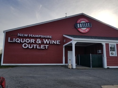 Red building with a sign reading "New Hampshire Liquor & Wine Outlet" and a white door.