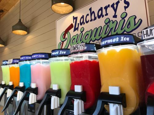 Colorful daiquiri machines lined up, featuring various flavors like strawberry, blue, and orange, at Zachary's.