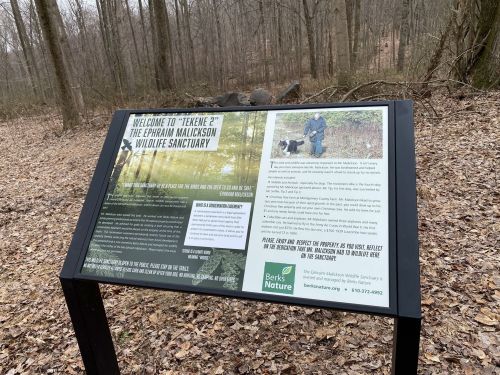 Sign at the Epman Malickson Wildlife Sanctuary, detailing the sanctuary's features and visitor information in a wooded area.