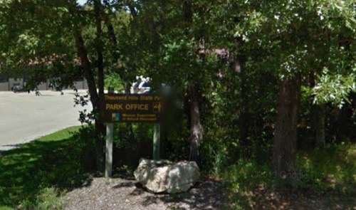 Sign for Thousand Hills State Park Park Office, surrounded by trees and a rocky area.