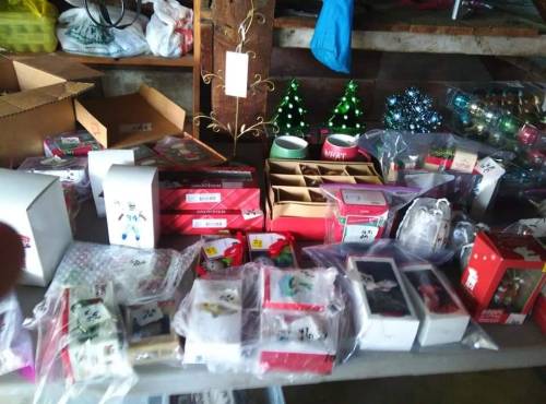 A table filled with various holiday-themed boxes, decorations, and gifts in a garage setting.