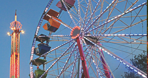 A colorful Ferris wheel and a tall ride illuminated with lights against a twilight sky.