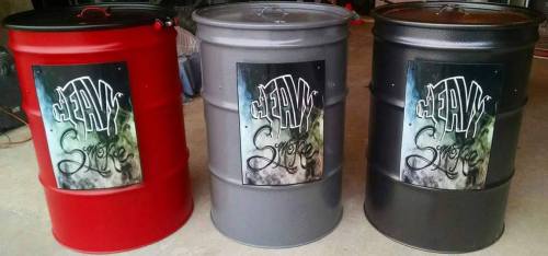 Three metal barrels in red, gray, and black, each featuring a sign with the text "Heavy Smoke" in a stylized font.
