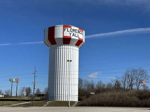A tall water tower with red and white stripes, labeled "FLORENCE Y'ALL," against a clear blue sky.
