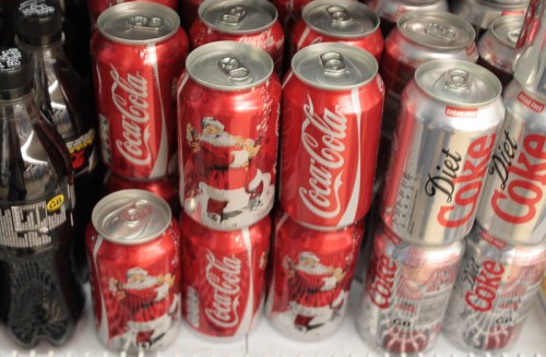 A display of Coca-Cola and Diet Coke cans, featuring festive holiday designs with Santa Claus.