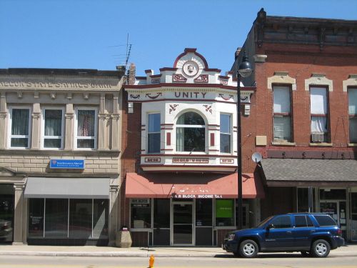 Historic building with "Unity" signage, featuring ornate architecture and a tax office below, set in a small-town street.