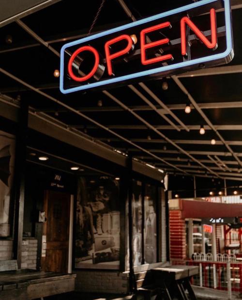 A glowing "OPEN" neon sign hangs outside a storefront, with a cozy, inviting atmosphere.