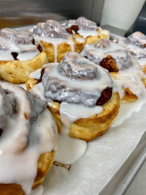 Freshly baked cinnamon rolls drizzled with creamy icing, arranged on a tray.