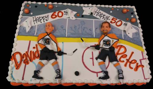 A decorated cake featuring two hockey players, celebrating David's 60th and Peter's 50th birthdays.
