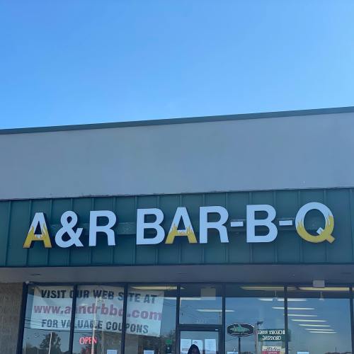 Sign for A&R Bar-B-Q on a storefront, with a clear blue sky in the background.