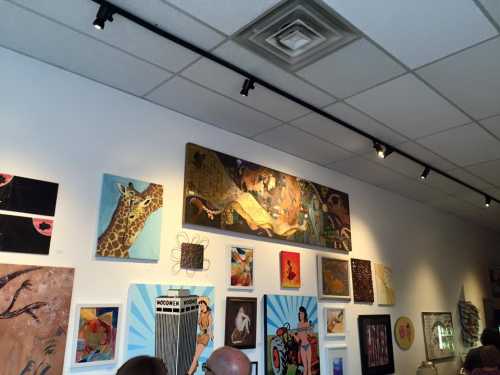 A gallery wall featuring various colorful artworks, including a giraffe painting and a large abstract piece.