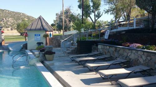 A serene pool area with lounge chairs, steps, and a small building surrounded by trees and mountains in the background.
