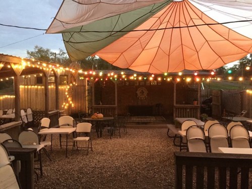 Outdoor seating area with colorful canopies and string lights, creating a cozy atmosphere in the evening.