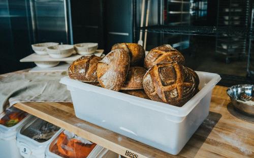 A container filled with freshly baked artisanal bread loaves on a wooden countertop.