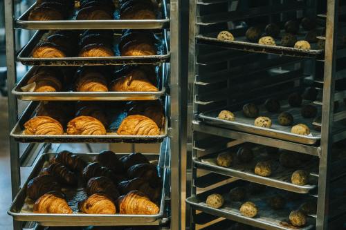 Trays of freshly baked croissants and cookie dough balls in a bakery display.