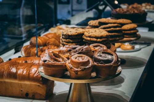 A display of various baked goods, including cookies, cinnamon rolls, and loaves of bread on a countertop.