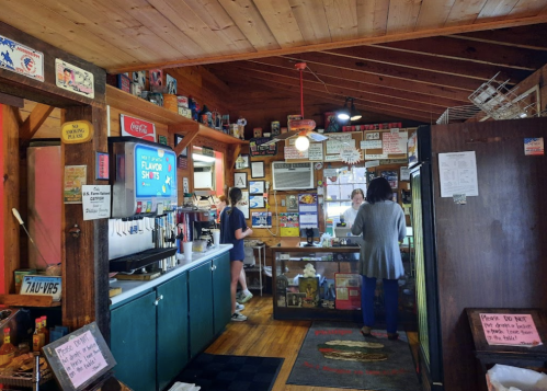 A cozy diner interior with wooden walls, vintage signs, and a counter where customers are being served.