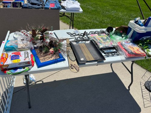 A table outdoors displaying various items, including kitchenware, toys, and decorative objects.