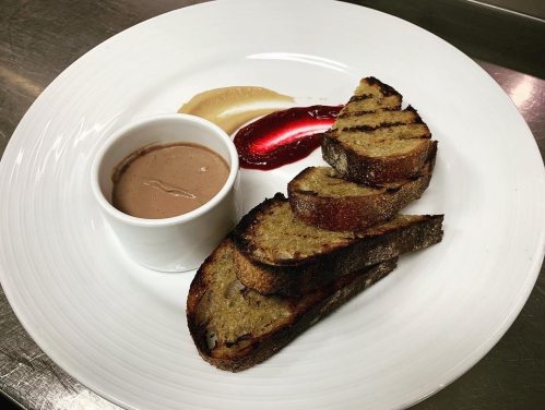 Grilled bread slices served with chocolate sauce and fruit puree on a white plate.