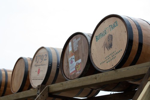 Three wooden whiskey barrels stacked on a rack, featuring labels for Buffalo Trace and 1792.