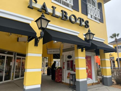 Exterior of a Talbots store with yellow walls, black awnings, and decorative lanterns.