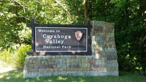 Welcome sign for Cuyahoga Valley National Park, surrounded by greenery and stone structure.