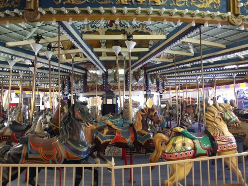 A colorful carousel with intricately designed horses, set under a vibrant canopy.