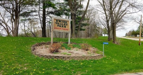 Sign for Swiss Valley Park at the entrance, surrounded by greenery and a small landscaped area.