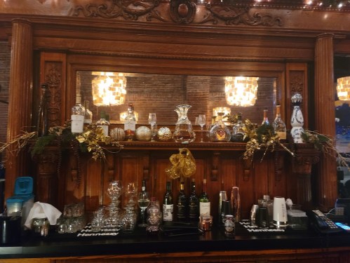 A beautifully decorated bar with various bottles, glassware, and festive accents against a wooden backdrop.