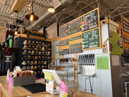 A cozy bar with a wooden counter, colorful drink menus, and a wall of beer taps in a well-lit space.