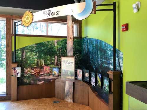 Exhibit titled "Listen to the Forest" featuring forest imagery and informational displays in a nature center.