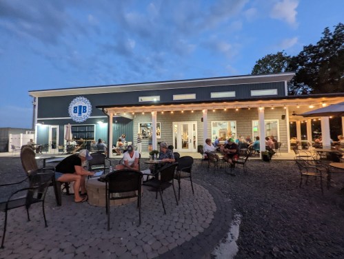 A cozy outdoor seating area at a café, with people enjoying drinks under string lights at dusk.