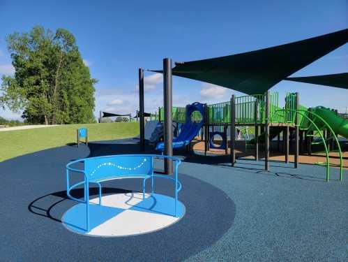 A colorful playground featuring slides, climbing structures, and a spinning merry-go-round on a sunny day.