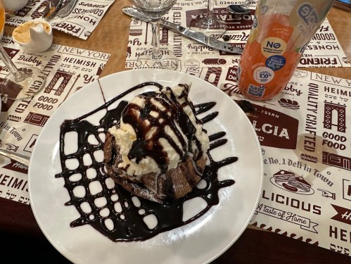 A dessert plate featuring a chocolate cake topped with whipped cream and drizzled with chocolate sauce.