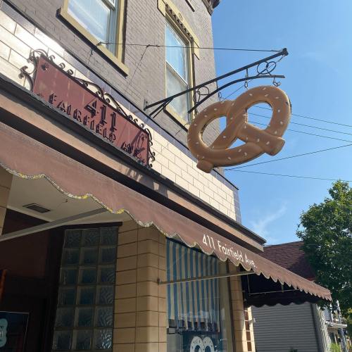 A storefront with a sign reading "411" and a large pretzel hanging above the entrance on a sunny day.