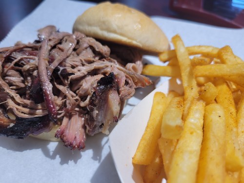 A plate featuring a pulled pork sandwich and a side of golden French fries.
