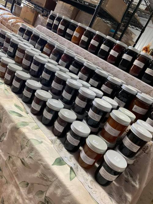 A display of various jars filled with preserves, neatly arranged on a table with a floral tablecloth.