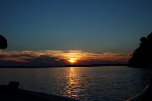 A serene sunset over a calm lake, with colorful clouds reflecting on the water's surface.