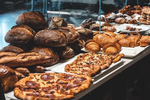 A display of various baked goods, including loaves of bread, croissants, and pizzas, arranged on a table.